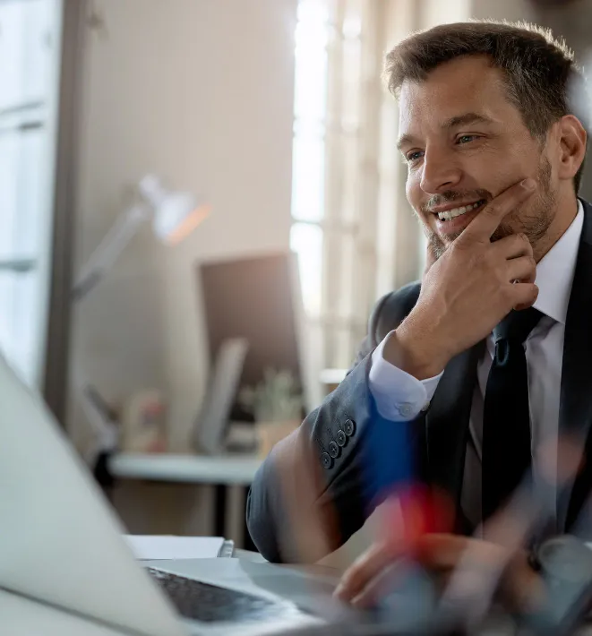 Gestor comercial sorrindo enquanto analisa os dados de vendas no notebook