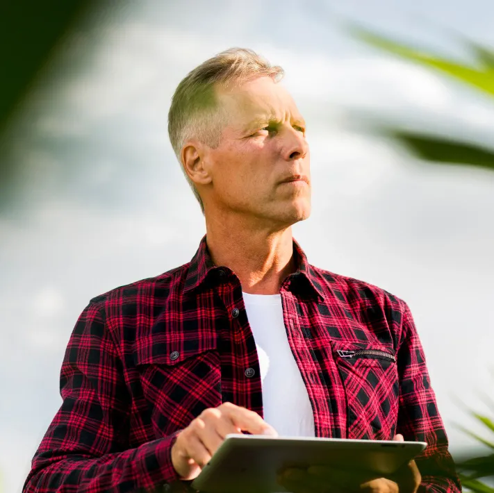 Vendedor consultando o aplicativo em um tablet no meio da lavoura